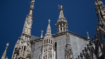 Fototapeta na wymiar Golden Madonnina on the roof of Duomo cathedral. Milan, Italy.