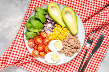 Healthy lunch bowl: egg, tuna, avocado, cherry tomatoes, corn salad, onion