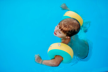 Little boy enjoying summer in a pool.