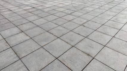 Gray tiles on the sidewalk in the city outdoors. Background and texture with lines and squares of tiles. Abstract frame, copy space, place for text