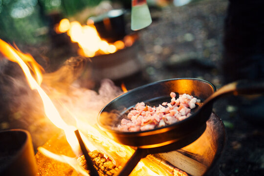Bacon frying in pan over campfire