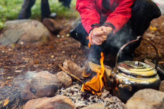 Woman warming hands over campfire in forest