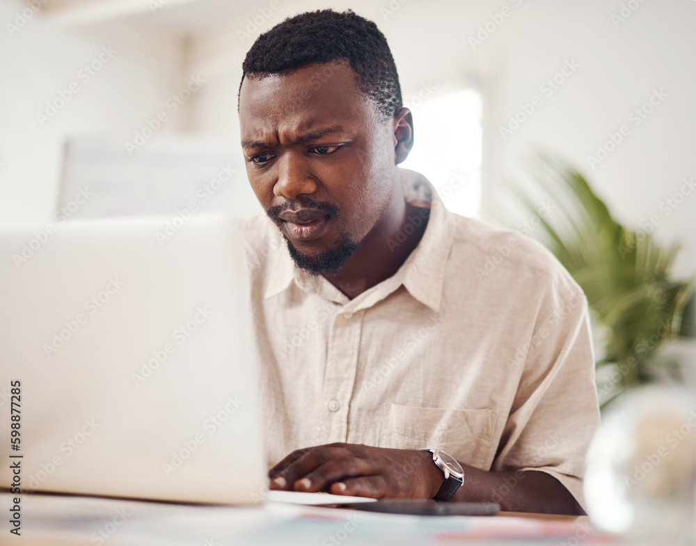 Wall mural What is happening now...a young businessman looking confused while using a laptop in an office.