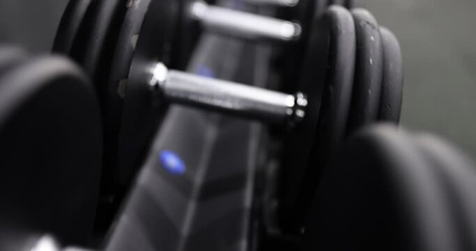 Lot of dumbbells lying neatly in row in gym closeup 4k movie slow motion. Sports training concept