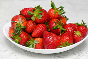 strawberries in a white plate on a marbled kitchen table