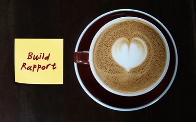 Coffee cup with handwritten text note BUILD RAPPORT, to remind self to building relationships with others in which both parties feel supported and understood to accomplish career goals