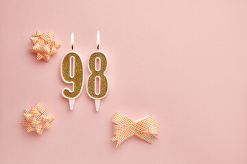 Candles with the number 98 on a pastel pink background with festive decor. Happy birthday candles....