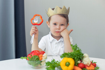 .Unhappy little boy refuses to eat vegetables, sad child holding a piece of pepper on a fork