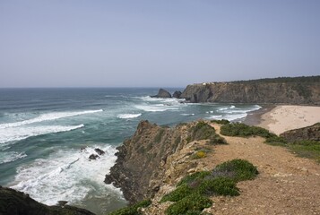 Wonderful landscapes in Portugal. Scenic coastline in Odeceixe. Praia de Odeceixe view from the cliff. Wavy sea. Rocky skerries. Sunny spring day. Selective focus