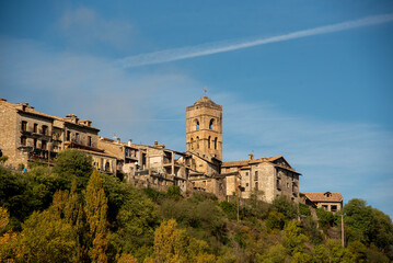 Panoramic view of the tourist village of Ainsa in Huesca, Aragon, made up of small brick and wooden houses next to a large medieval-style church, all surrounded by an impressive natural landscape.