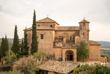 Fototapeta na wymiar Church of Santa María la Mayor, from medieval times and built in brick in the tourist village of Alquezar in Huesca during a cloudy day.