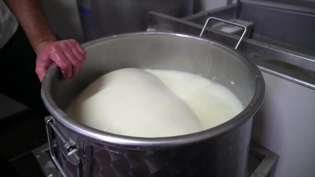 Pouring hot rennet water over cheese
