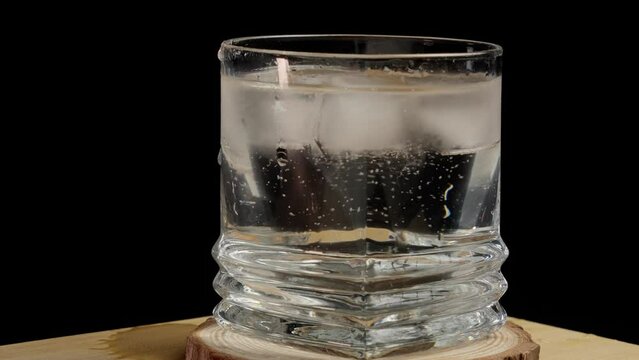 stirring sparkling  drink with ice - black background (4k - slow motion)[ high quality colors]