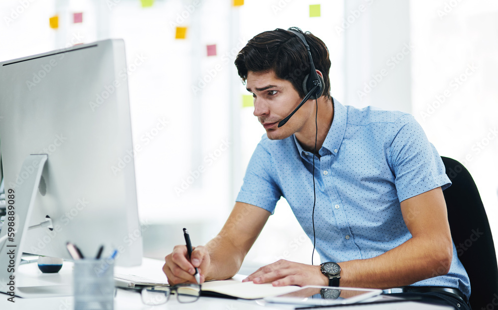 Poster Working his hardest to find the best solution. a young businessman using a headset while working on a computer in an office.