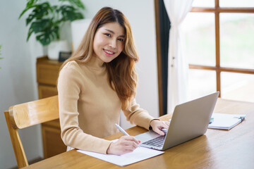 Happy beautiful Asian Woman. Business woman working from home with laptop Financial Home work space concept.