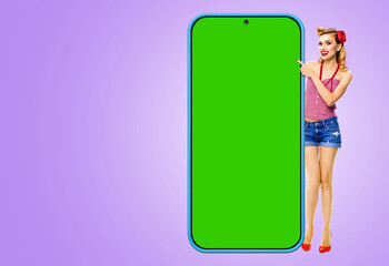 Full body beautiful woman in pin up, show big cell phone, mobile smartphone. Pinup girl hold peep from cellphone green chroma key mockup screen, isolated light purple violet background. App