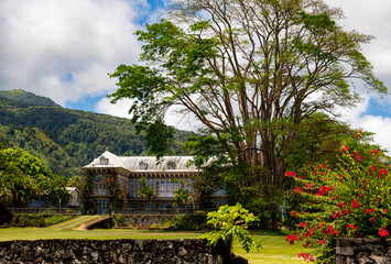 Big historic manor house in Saint Pierre on Martinique island (France) with opulent old garden and tropical vegetation. Mount Pelée volcano in background. Public museum and caribbean rum distillery.