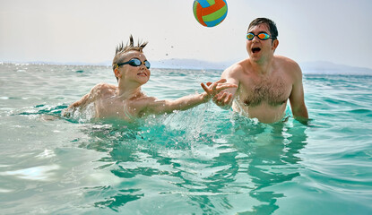 Happy family in swimming goggles, father and son bonding, play ball, swim in the sea looking at view enjoying summer vacation. Togetherness Friendly concept
