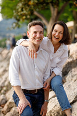 Portrait of stylish casual couple in love in white embracing each other at the Italian lake stone coast 