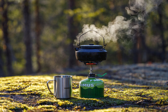IMATRA, FINLAND - 19 APRIL, 2023: Kettle boiling on a gas stove in the forest. Background is blurred.