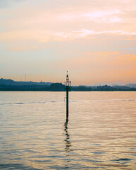 A Pole in The Sea in The Evening with An Orange Sky Background