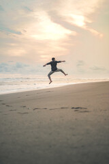 A happy young man jumping in the beach on Solo vacation at the Samas beach in Bantul Regency