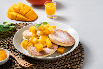 Delicious Japanese souffle pancake with dice mango and jam on gray table background.