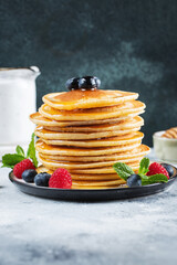 Delicious pancakes, with fresh blueberries, raspberry and maple syrup or honey on a dark background