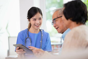 Fototapeta premium Health care consultation by young Asian woman nurse give a friendly consult to couple elderly by tablet. Concept Nursing home care.