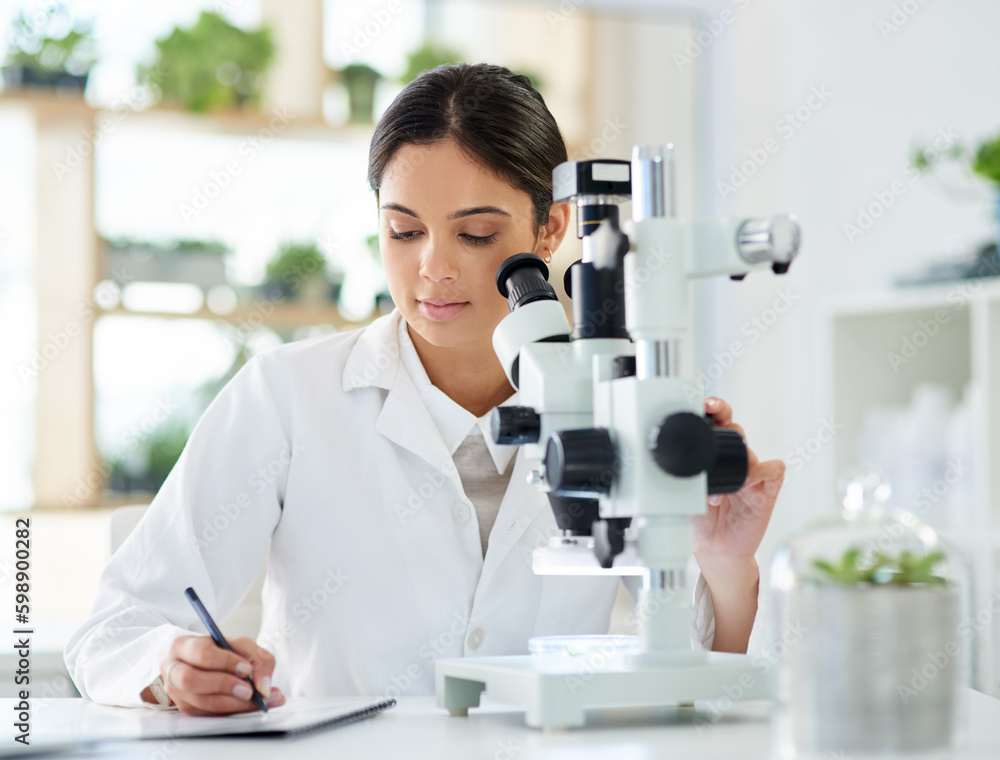 Aufkleber Noting down a new breakthrough. a young scientist writing notes while using a microscope in a lab.