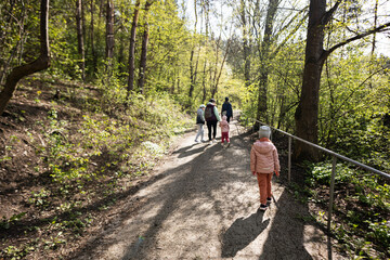 Back of mother with small children hiking outdoors in spring nature.