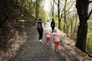 Fototapeta premium Back of mother with small children hiking outdoors in spring nature.