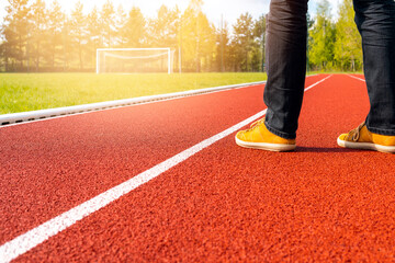 Man standing on the empty stadium with football gate and running track