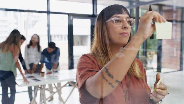 Creating new content is her craft. a young businesswoman brainstorming with notes on a glass wall in an office. - Powered by Adobe
