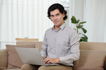 Portrait of smiling businessman working on laptop at home