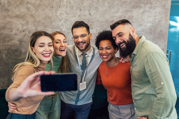 Happy group of coworkers taking a selfie at the office