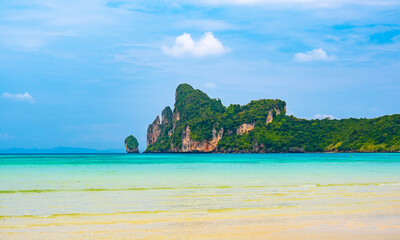 Fototapeta premium Landscape view of coastline with limestone rock and boats on ocean at Ko Phi Phi islands, Thailand. Concept of exotic tropical vacation and beautiful nature in paradise