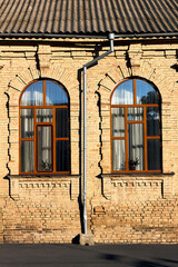 Two windows in wall of a the red brick building in old house. Element of architecture.