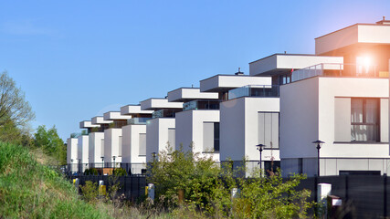 Terraced family homes in newly developed housing estate. The real estate market in the suburbs. New single family houses in a new development area. Residential homes with modern facade.  - obrazy, fototapety, plakaty