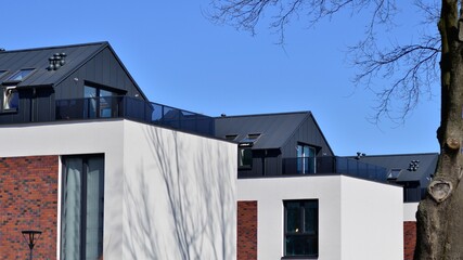 Terraced family homes in newly developed housing estate. The real estate market in the suburbs. New single family houses in a new development area. Residential homes with modern facade. 