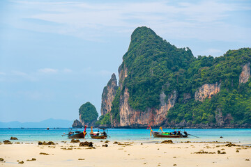 Landscape view of coastline with limestone rock and boats on ocean at Ko Phi Phi islands, Thailand. Concept of exotic tropical vacation and beautiful nature in paradise