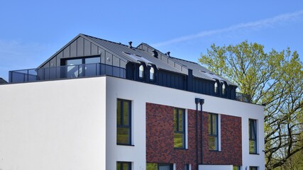 Terraced family homes in newly developed housing estate. The real estate market in the suburbs. New single family houses in a new development area. Residential homes with modern facade. 
