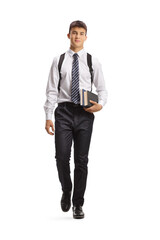 Full length portrait of a male student carrying books and walking towards camera