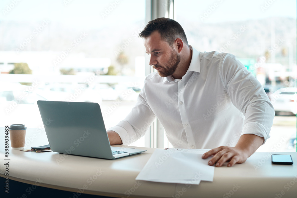 Sticker Having the correct paperwork matters. a young car salesman filling out paperwork in his office.