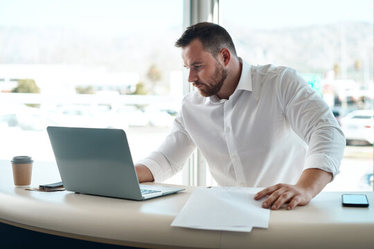 Having The Correct Paperwork Matters. A Young Car Salesman Filling Out Paperwork In His Office.