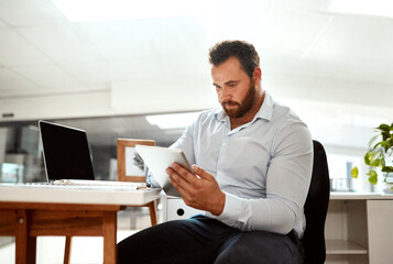 Setting new ideas into action. a young businessman using a digital tablet in an office.