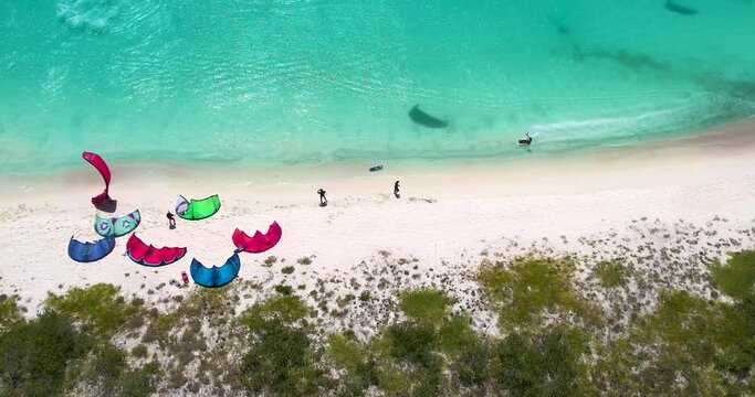 Aerial top down man kitesurf along shore beach, kite camp on crasqui tropical island.