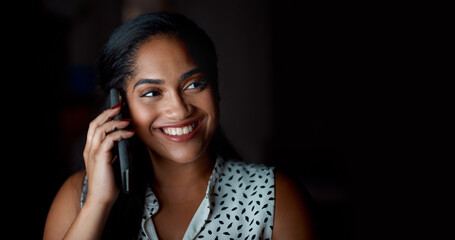 It takes dedication to grow your career. a young businesswoman talking on a cellphone in an office at night.