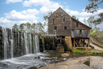 Yates Mill in North Carolina with Waterfall, pond< building, and Waterwheel.