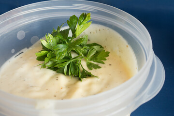 Close-up of a sprig of fresh parsley on homemade aioli with a creamy texture and rich flavor ready to enhance any dish with prime. Traditional food.